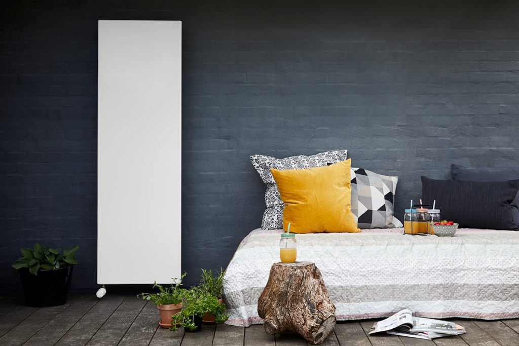 White vertical Hudevad radiator in a summer setting